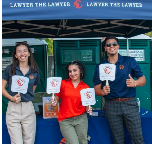 LA LAW team at Connecticut community event holding branded signs under Lawyer The Lawyer tent
